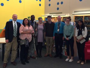 Dr. Lazar and students standing side-by-side, smiling at the camera. Behind them are cases of books.